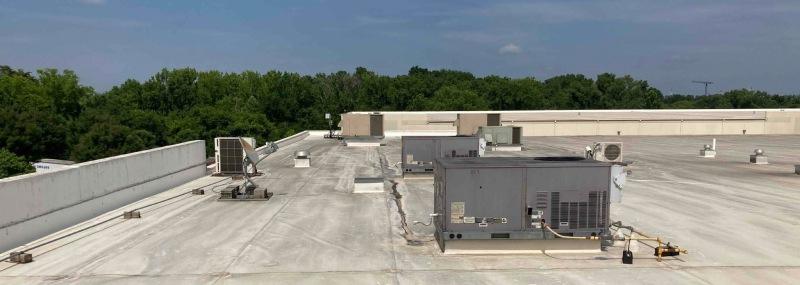 hvac units on a commercial roof with trees in the background